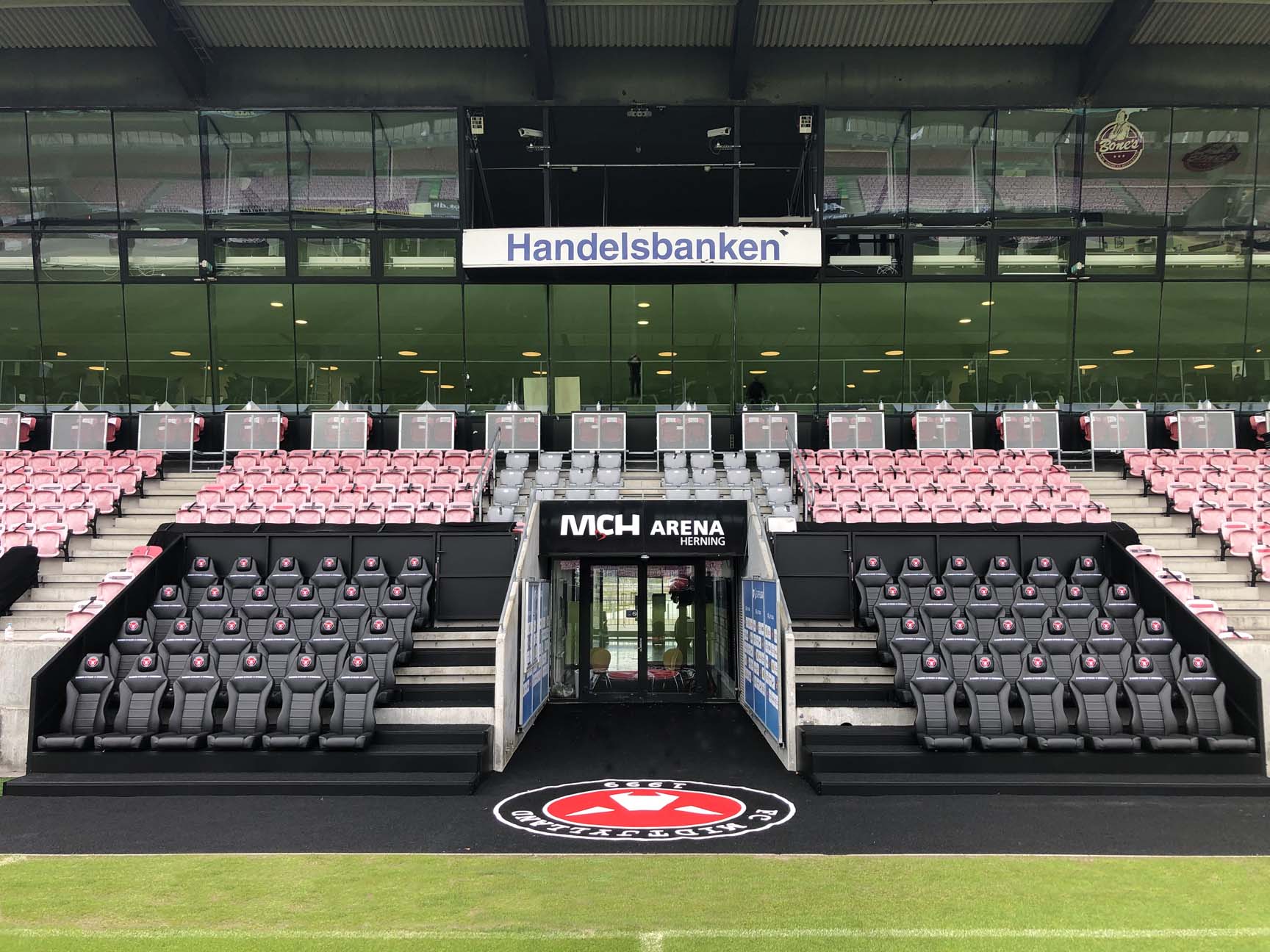 bilde av stadion med svarte innbytterbenker og tribune med røde seter