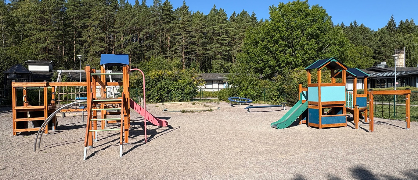 Lekplats på förskola i Sigtuna med två lekställningar, rutschkanor, klätternät och balanslek.