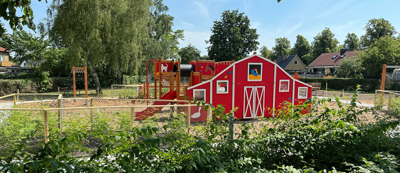 Lekplats med bondgårdstema bland lummiga träd i ett bostadsområde