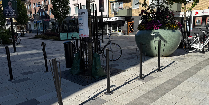 Svarta cykelpollare placerade längs en trottoar i stadsmiljö för säker och smidig cykelparkering.