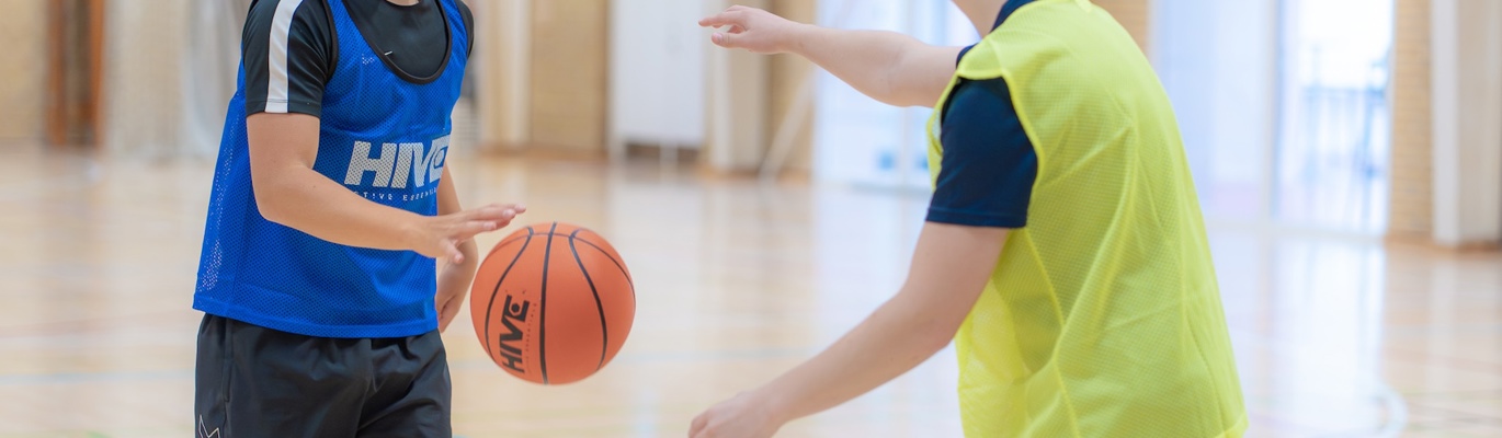 Gutter som spiller basketball i skolens idrettshall