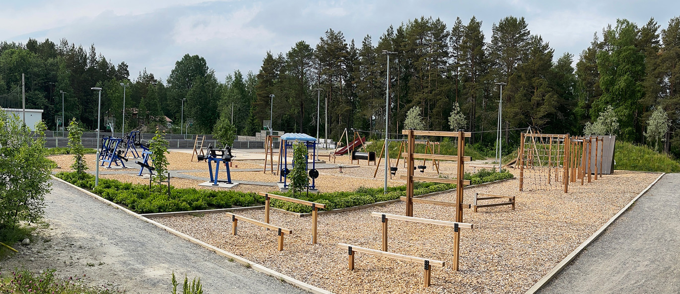 Stor park med hinderløype og et utendørs treningsområde med blå treningsapparater.