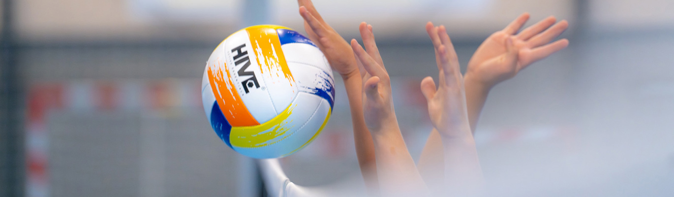 Nærbilde av en volleyball som skytes over nettet i en idrettshall