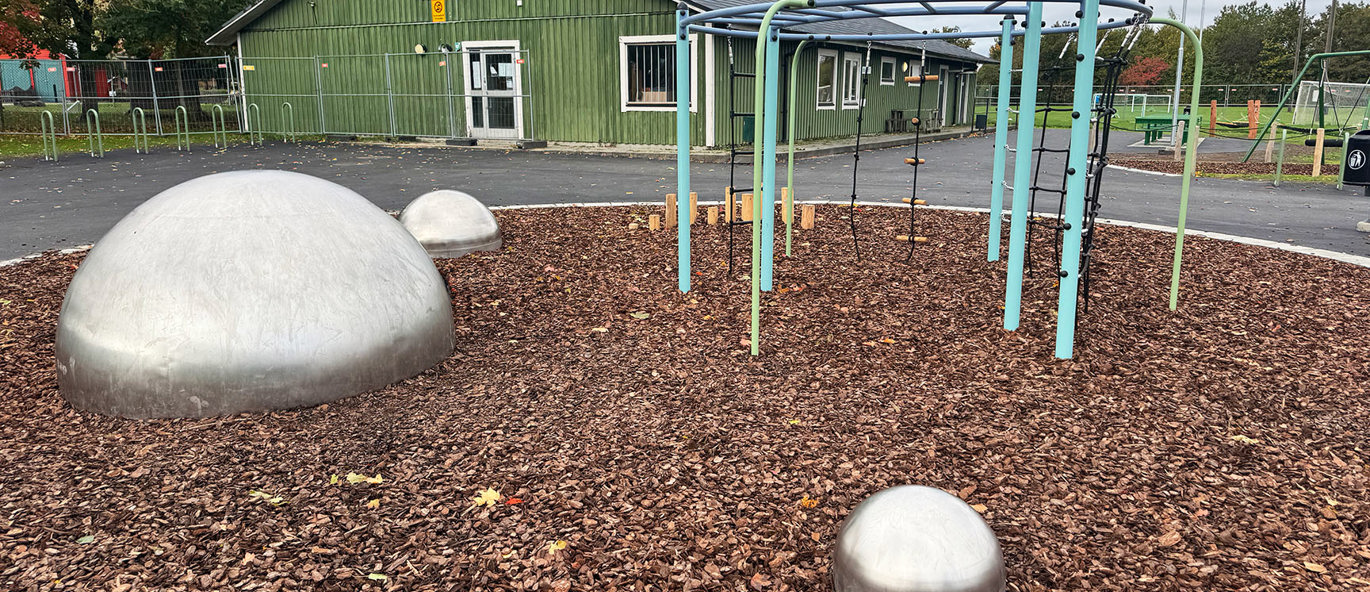 Lekeplass på Näsby IP i Kristianstad med klatrestativ, balansekuler og kuppelformede balanseelementer i tilknytning til idrettsanlegget.