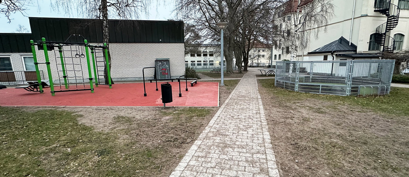 En steinlagt gangvei leder frem til en fargerik hinderløype og en rund fotballbane.