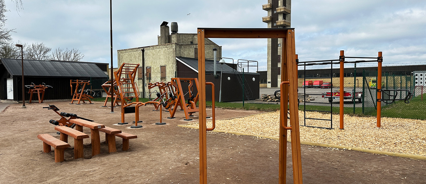 Utegym i Stadsparken i Kristinehamn med styrketräningsmaskiner, träningsställning och sittplatser i en naturnära parkmiljö.