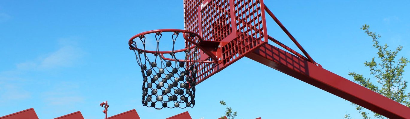 Rött basketstativ utomhus med korg och nät mot blå himmel