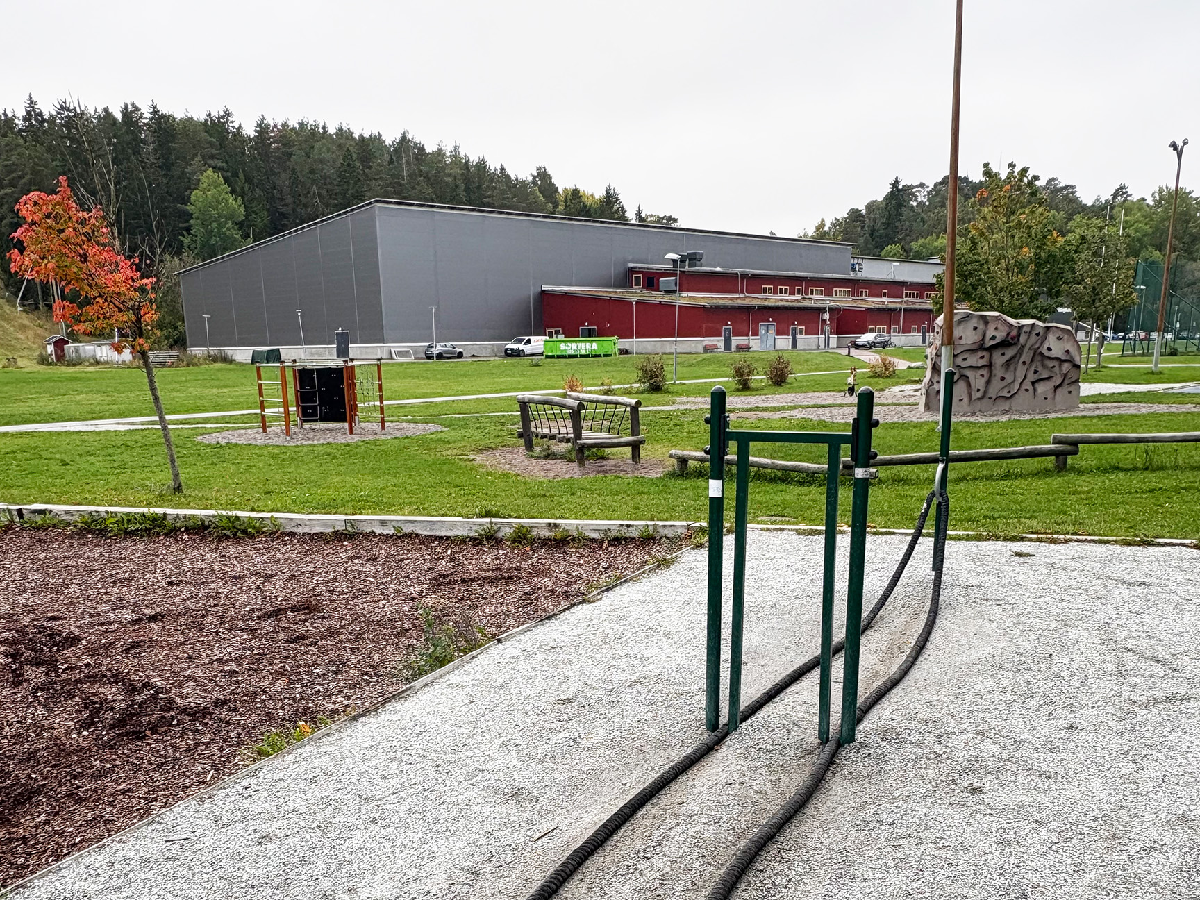 Battle rope-station i förgrunden med lekställning och klättersten på gräsytan bakom, Prästängarna i Sigtuna.
