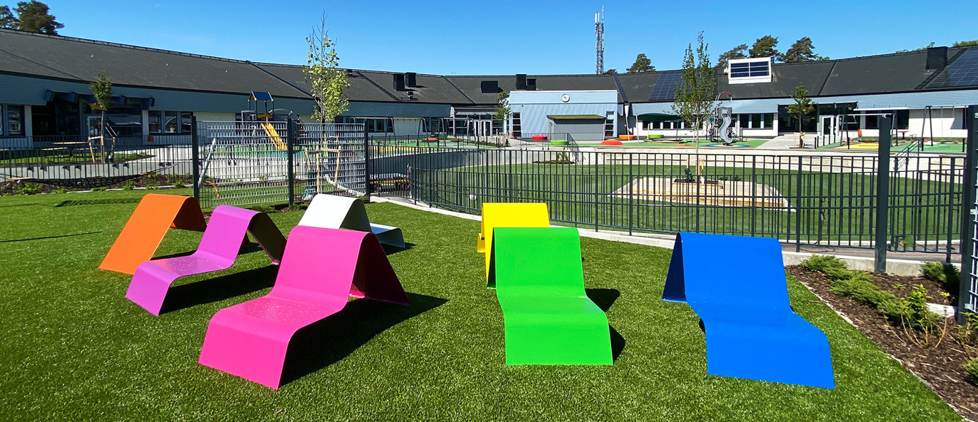 Färgglad skolgård med marktrampolin, rutschkana och klätterställning