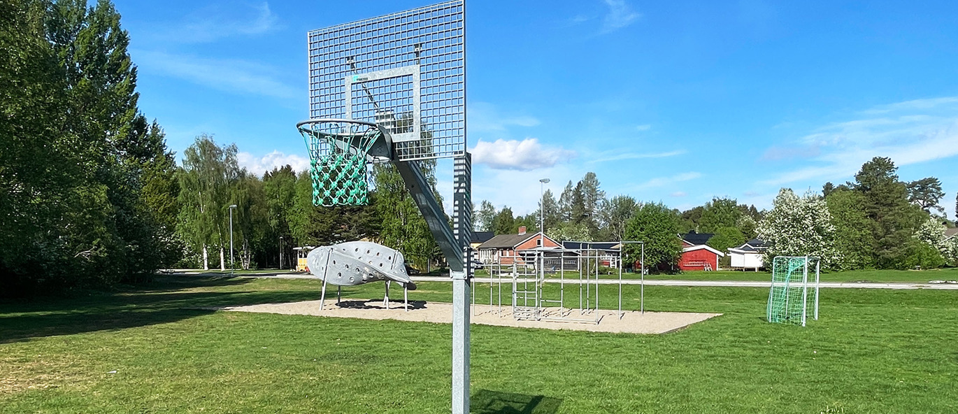Lekplats med parkourställning, klätterställning och basketkorg i park i Storuman.