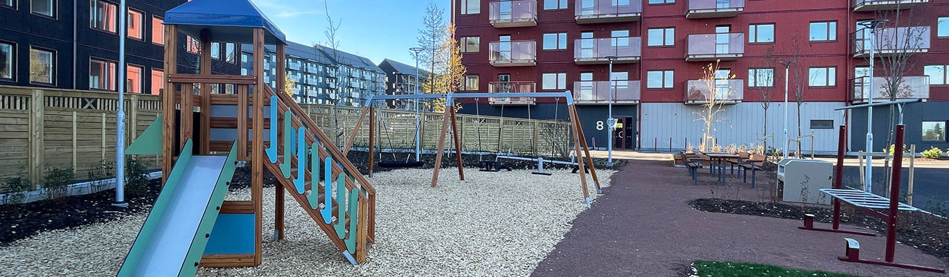 Gårdsmiljö i bostadsområde med lekutrustning, gungor och gröna vistelseytor som bidrar till en attraktiv, trygg och välfungerande utemiljö för fastighetsägare och fastighetsbolag.