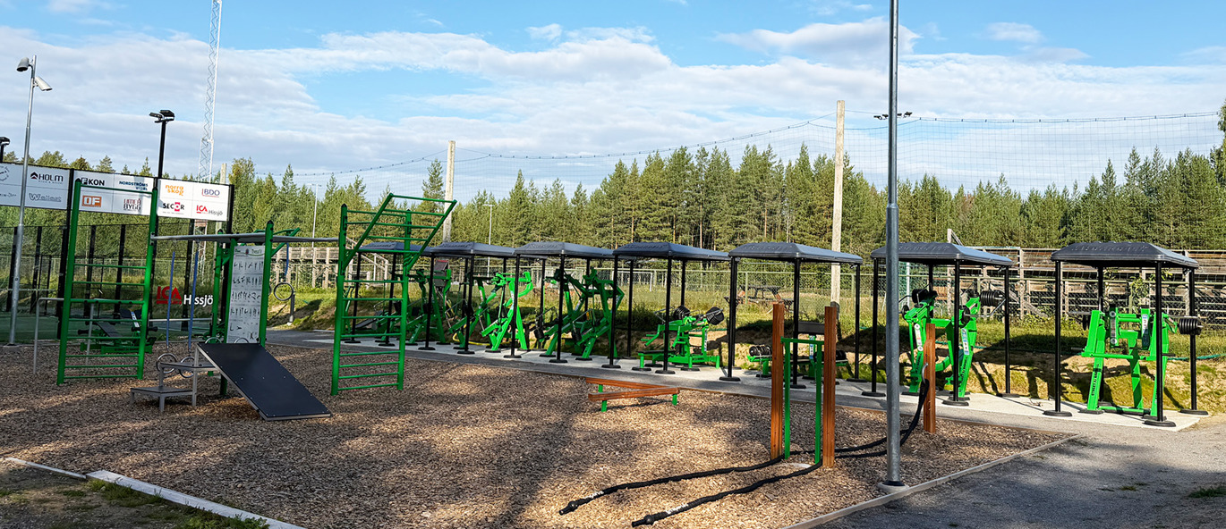 Utegym med gröna träningsredskap och en funktionell träningsställning vid Hissjö IP i Umeå.