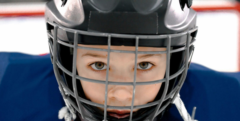 En hockeyhjälm på ett barn iklädd hockeyutrustning
