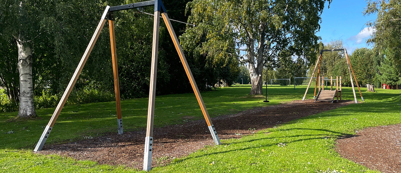 Grønn lekepark med zipline og rødt klatrenett.