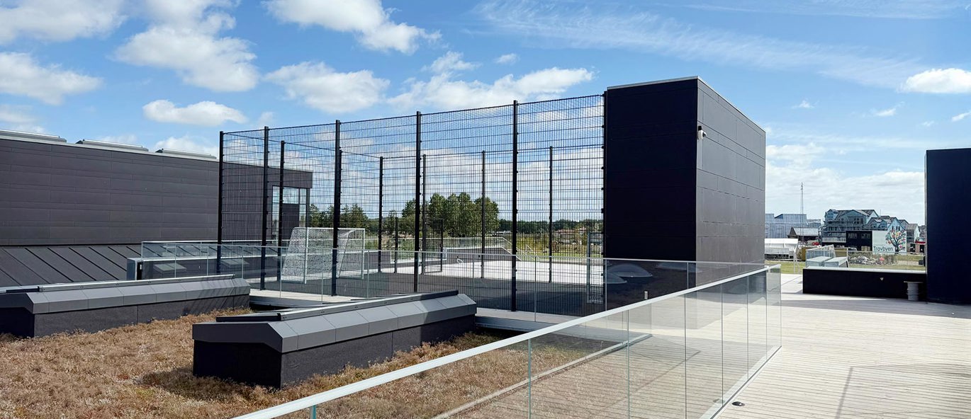 Spesialdesignet ballbane med høyt gjerde på taket av en skole