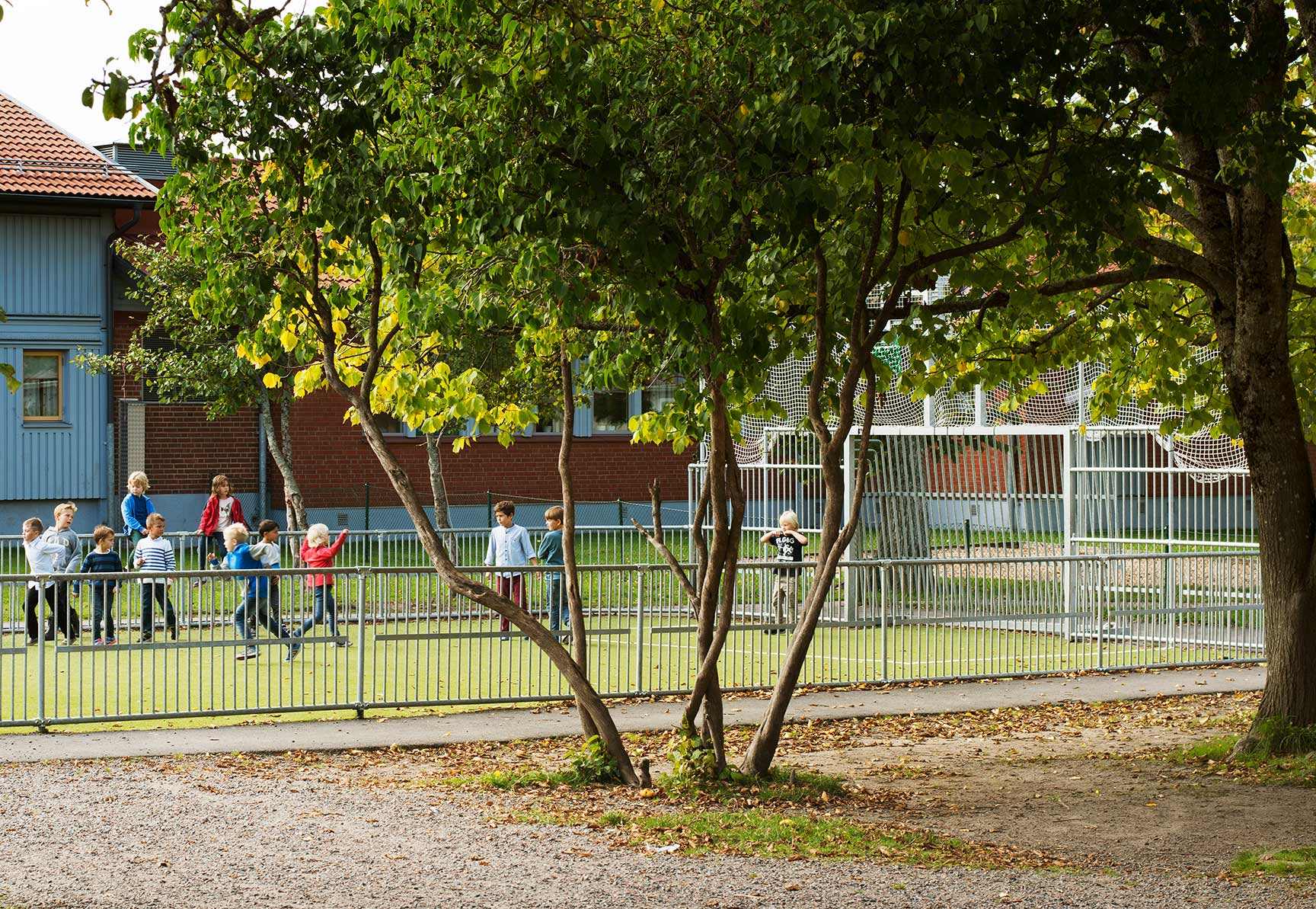 Barn i rörelse vid en öppen och tillgänglig multiarena på skolgård i grön utomhusmiljö