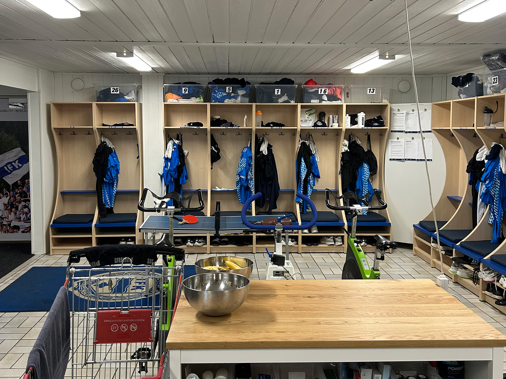 IFK Värnamos omklädningsrum med specialanpassade omklädningsbås, blå sittdynor, krokar för kläder och skohyllor under bänkarna.