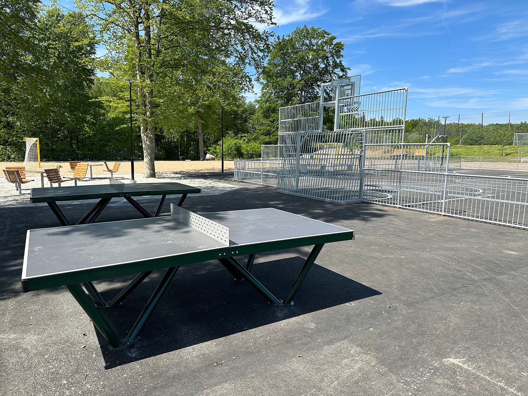 Aktivitetsyta på campingplats med bordtennisbord, multiarena och ytor för lek, träning och gemenskap utomhus.