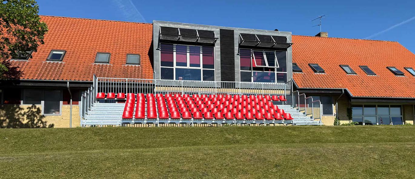 Tribune med 102 røde sitteplasser ved AaBs treningsanlegg og oppvisningsbane