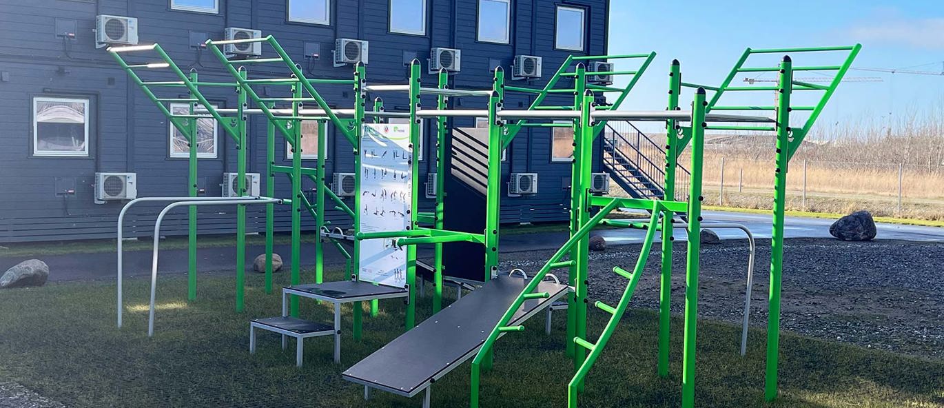 Grønt treningsstativ foran boliger på åpent område