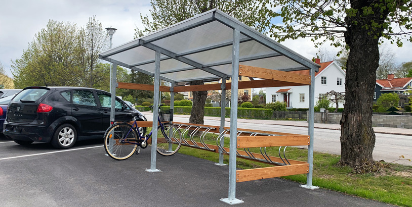 Cykelställ med tak för väderskyddad cykelparkering i bostadsområde.