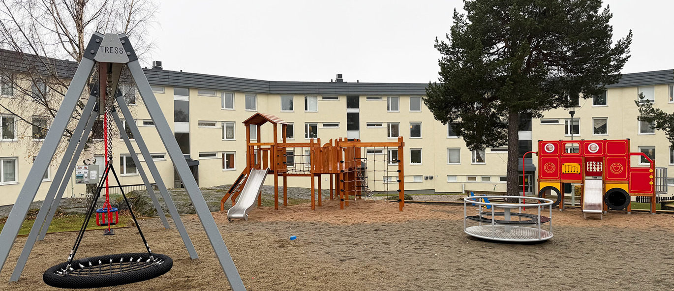 Lekeplass i boligområdet Ortvikshöjden i Sundsvall med huskestativ, lekeapparat med rutsjebane, karusell og en rød brannbil for lek.