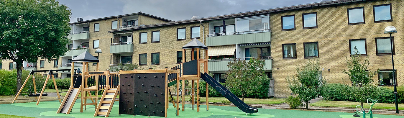 Modern lekplats i bostadsområde med klätterlek, rutschkanor och fallskydd som bidrar till en attraktiv, trygg och välanvänd utemiljö för fastighetsägare och fastighetsbolag.