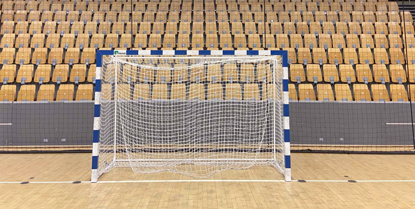 Handbollsmål med nät framför läktare i en idrottshall