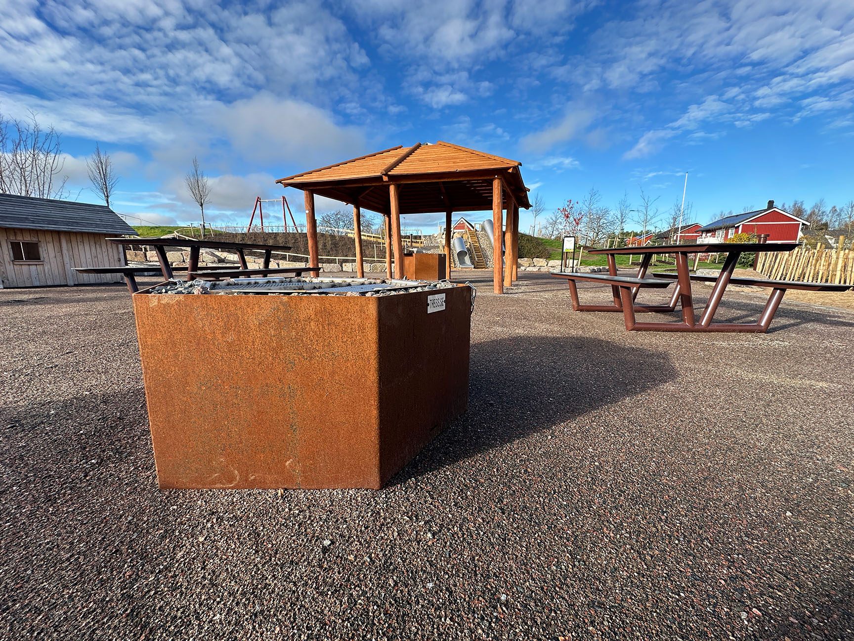 Udendørs mødested med udendørs parkgrill i cortenstål, bålhytte i træ og bordbænkesæt