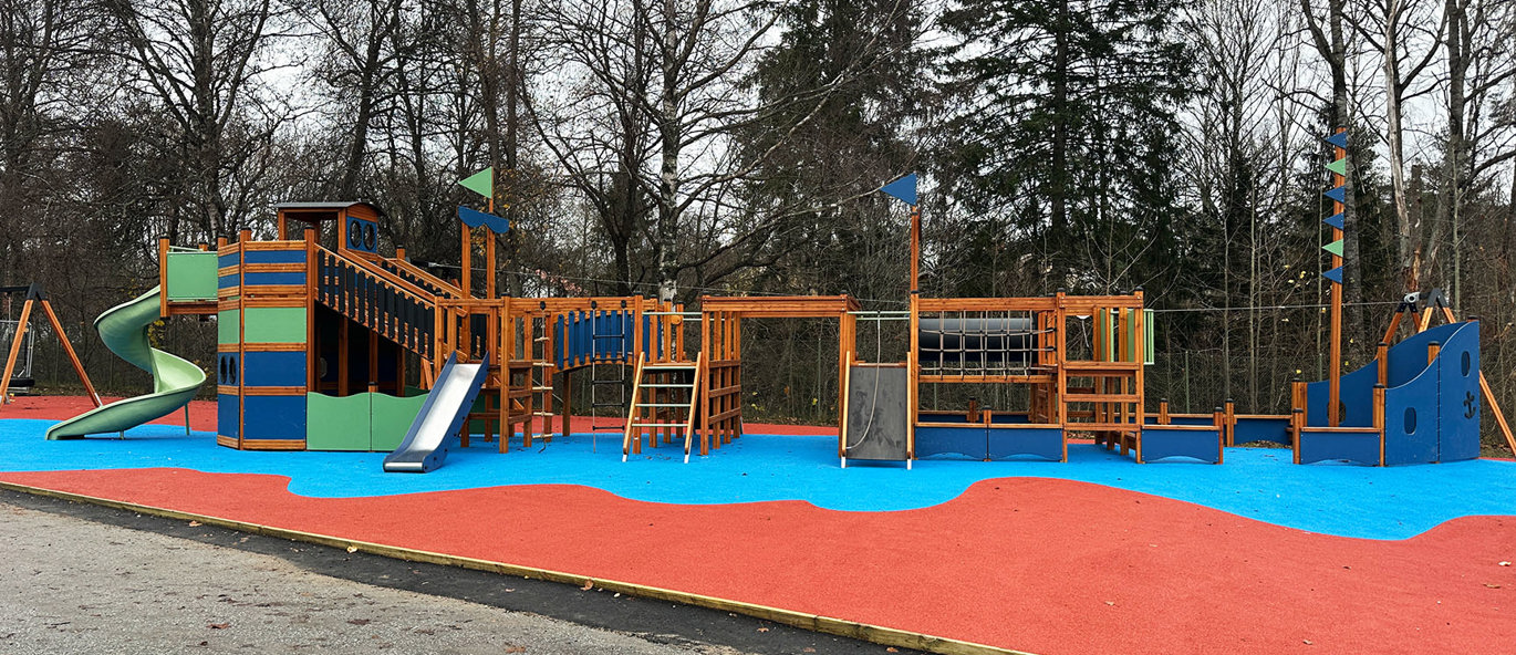 Lekplats med färgglatt gummiunderlag och ett megastort lekplatsfartyg.