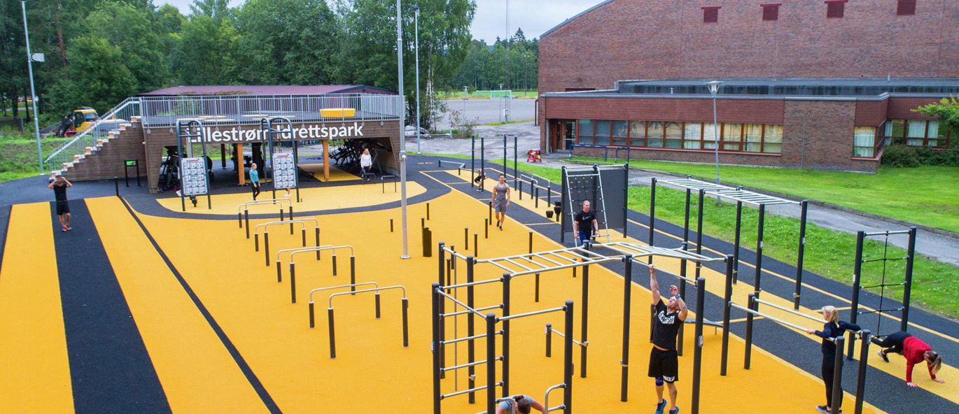 Träningspark med olika träningsredskap och träningsstationer på färgglatt underlag.