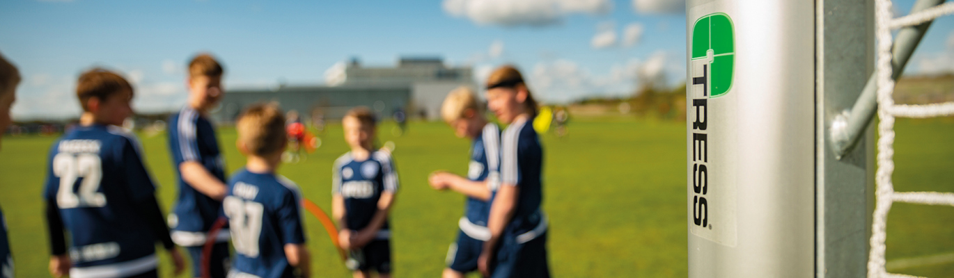 En gruppe unge fotballspillere står samlet ved fotballbanens fotballmål