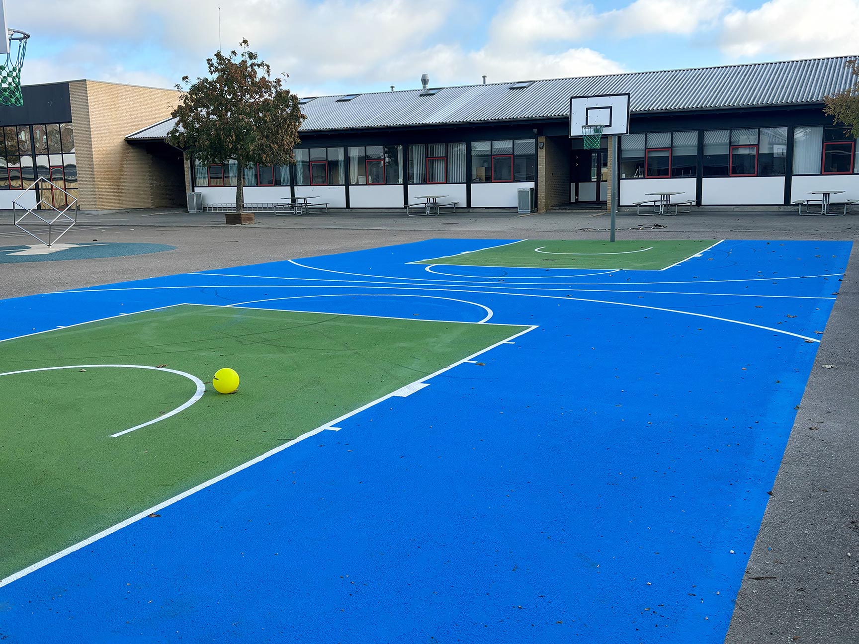 Opstreget basketballbane i blå og grønne farver i skolegård