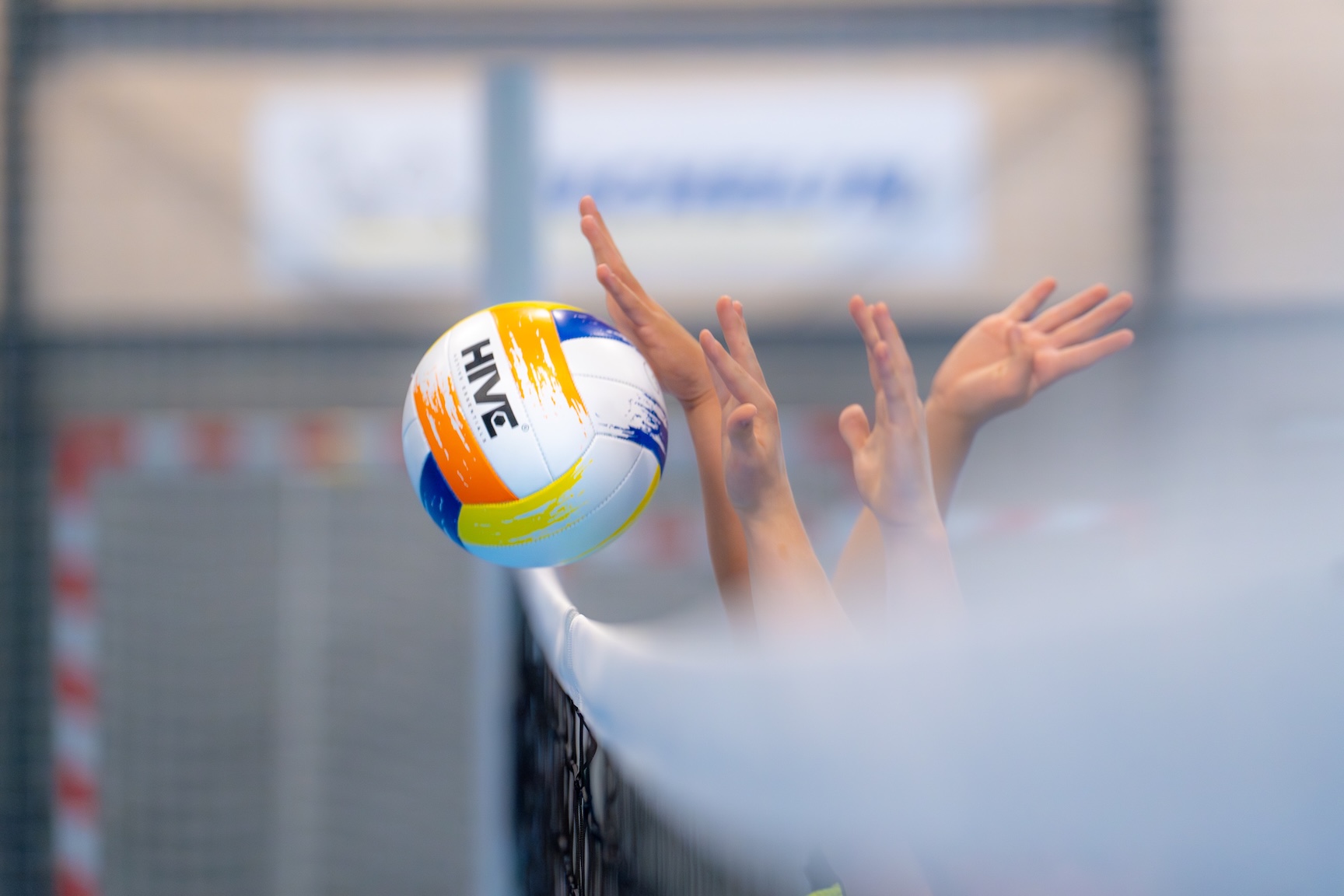 Close up billede af en volleyball, som skydes over nettet i idrætshallen