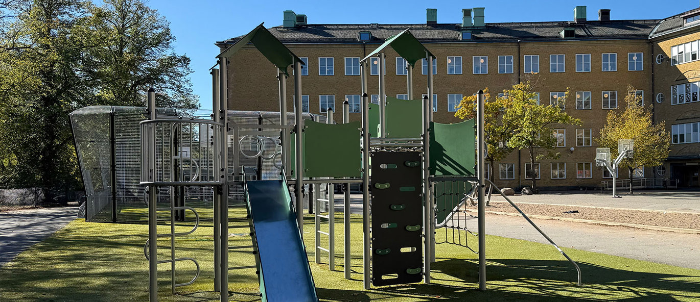 Lekställning med basketkorgar och multiarena i bakgrunden och grönt konstgräs. 