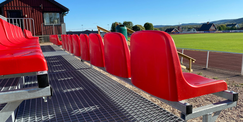 Sittplatsläktare med röda stolar vid idrottsplats