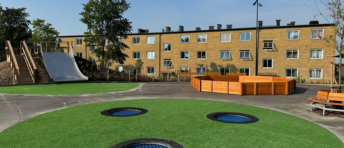 Skolgård vid Bjärshögsskolan i Åstorp med marktrampoliner, konstgräs, gagabollplan och rutschkana i en öppen lek- och aktivitetsmiljö.