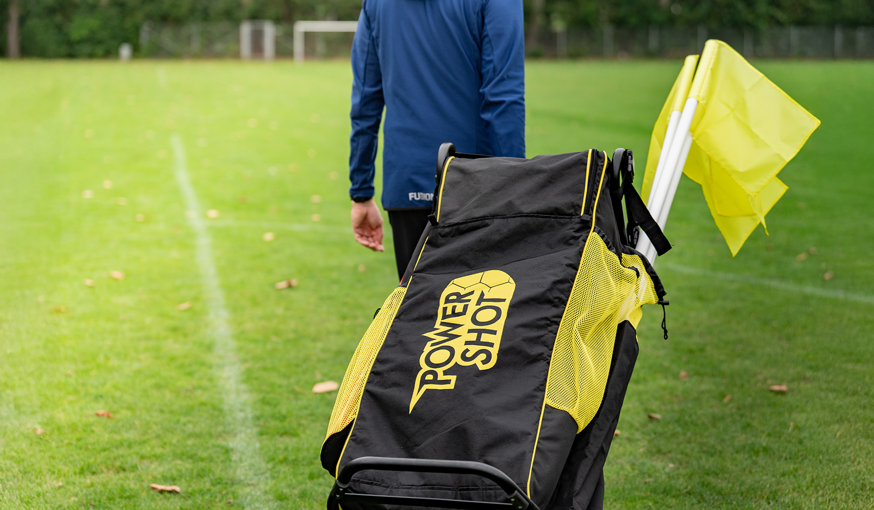 fodboldtræner med udstyrsvogn og hjørneflag på grøn fodboldbane