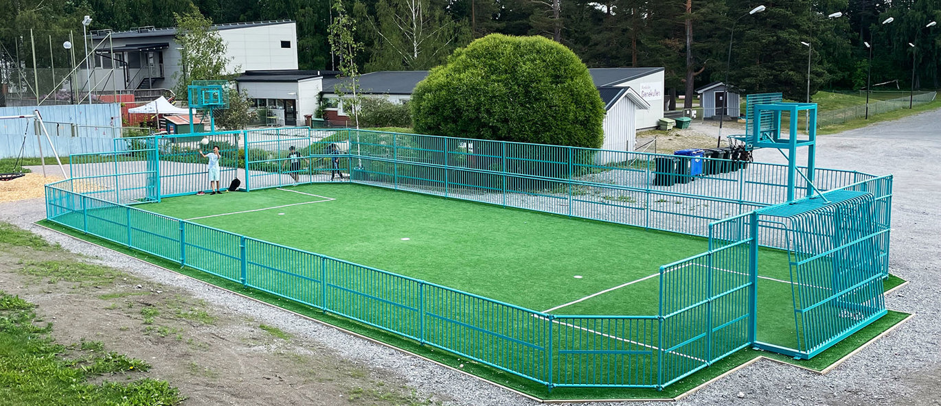 Multibane med mål og kunstgræs foran skole med børn