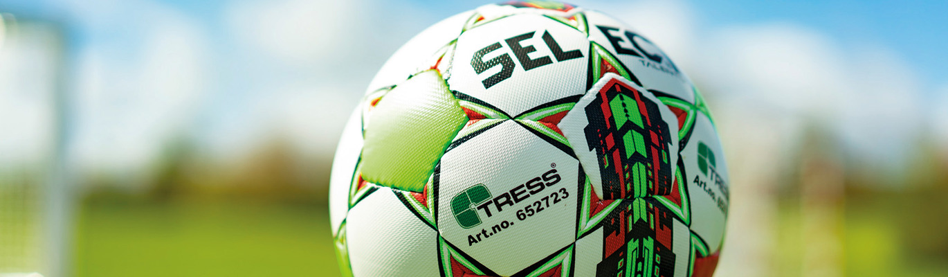 Fotball på grønn gressbane med blå himmel i bakgrunnen