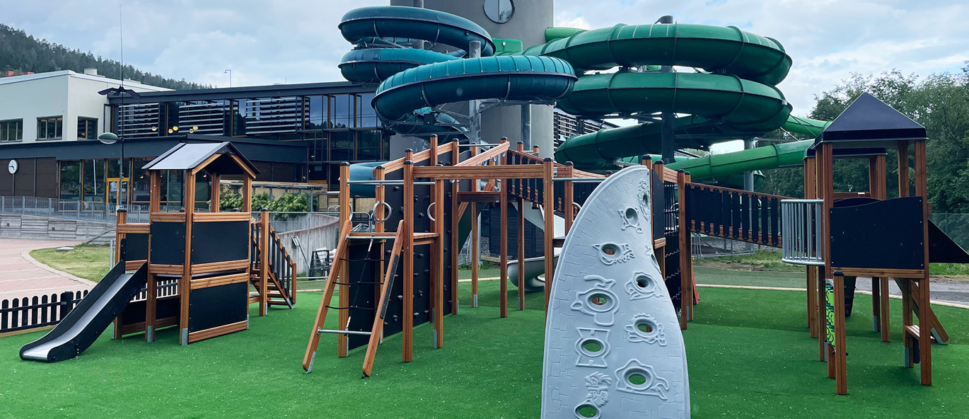 Kunstgræs underlag med to store legehuse med rutsjebane, klatrevægge og meget mere