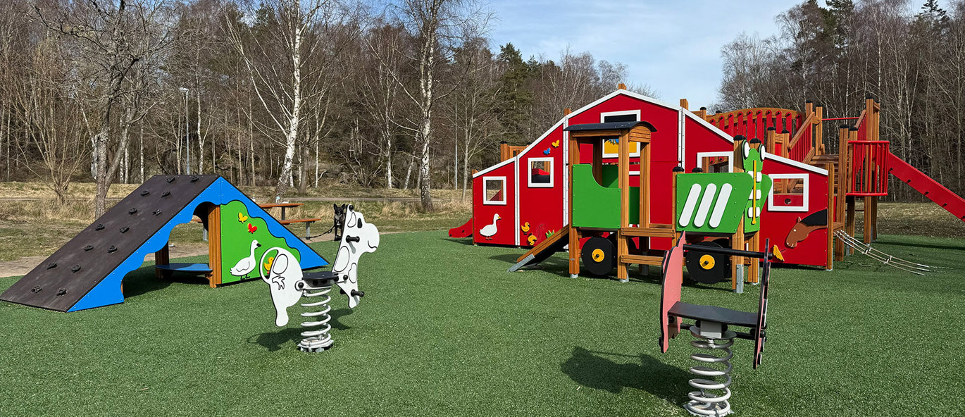 En lekpark med bondgårdstema; djur som fjädergungor, en traktor att klättra i och en lekställning som föreställer en bondgård.