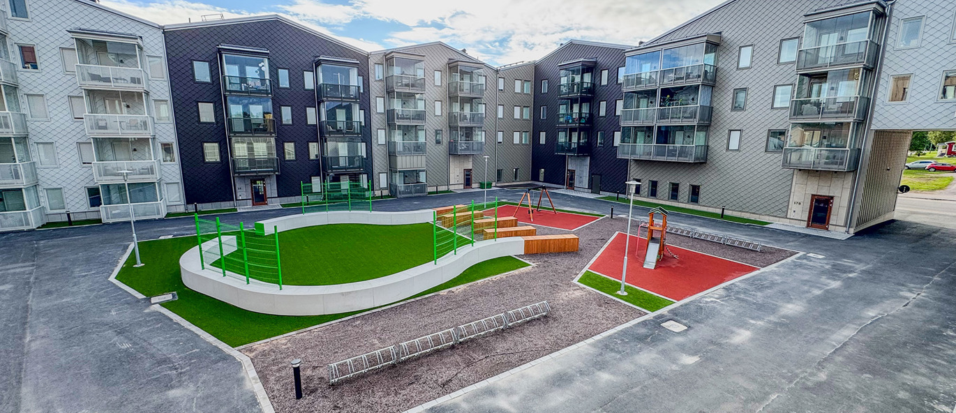 Bostadshus med innergård med lekplats och spontanidrottsplats på grönt konstgräs.